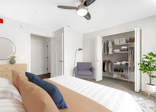 A bedroom with a bed, chair, and closet with organizers at Eagle Ridge Apartment Homes in Traverse City, MI