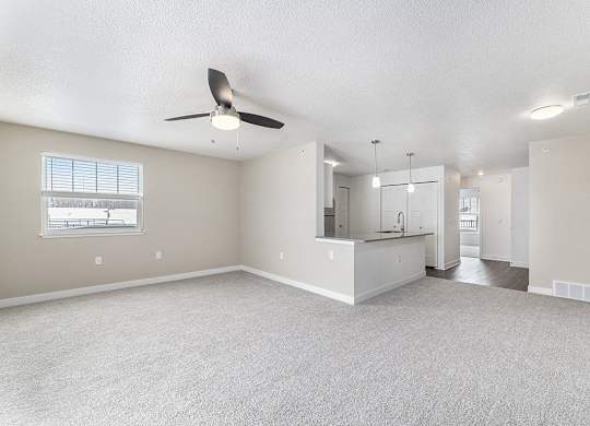 A spacious living room with a ceiling fan and a window at Eagle Ridge Apartment Homes, Traverse City, Michigan