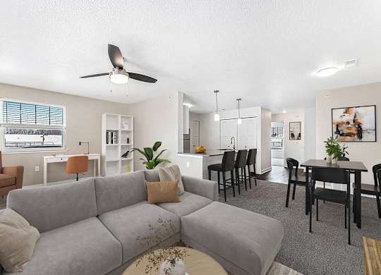 An enlarged living room with a grey couch and a ceiling fan at Eagle Ridge Apartment Homes in Traverse City, MI
