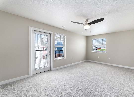 An enlarged living room with a ceiling fan and two windows at Eagle Ridge Apartment Homes, Traverse City, Michigan