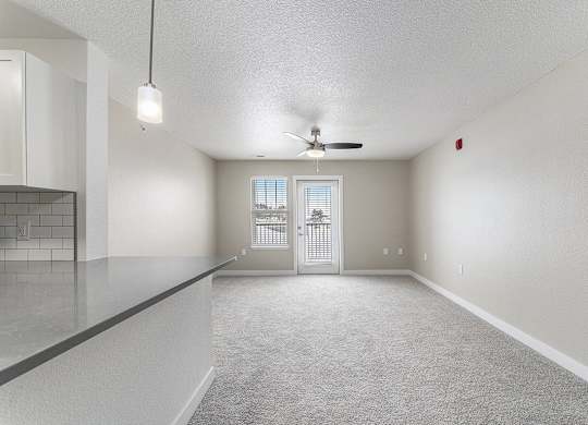 A spacious living room with a ceiling fan and a door leading to a patio at Eagle Ridge Apartment Homes, Traverse City, Michigan