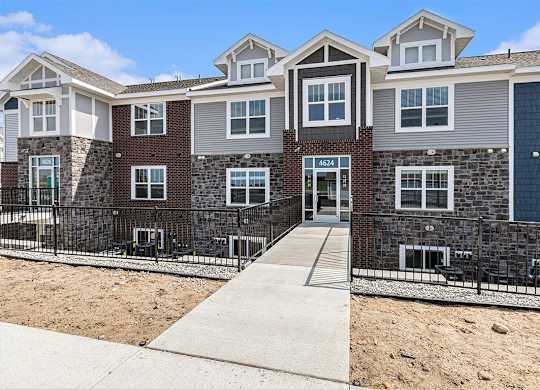 A multi-story residential apartment building with a sidewalk in front at Eagle Ridge Apartment Homes,  Michigan 49685