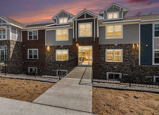 A modern apartment building with a sidewalk at Eagle Ridge Apartment Homes,  Michigan 49685