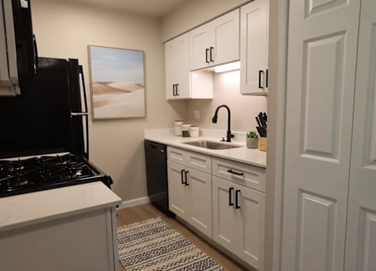 A kitchen with white cabinets and a black stove top oven.