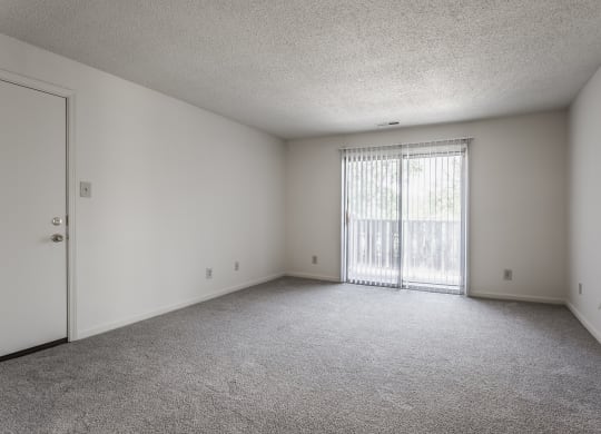 an empty bedroom with a door leading to a balcony at Bavarian Village Apartments, Indiana, 46235