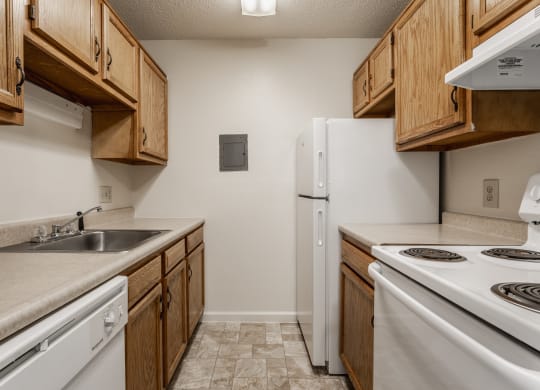 a kitchen with wooden cabinets and white appliances at Bavarian Village Apartments, Indianapolis