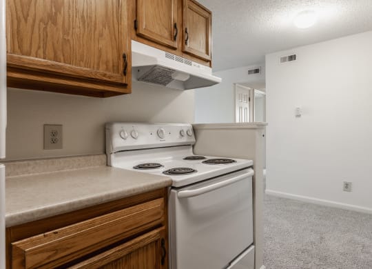 a kitchen with white appliances and wooden cabinets at Bavarian Village Apartments, Indianapolis