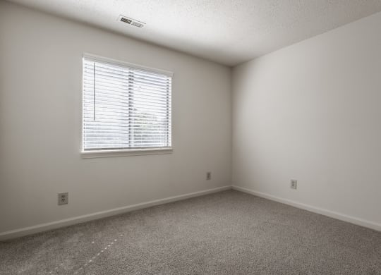 a bedroom with white walls and carpeted flooring and a window at Bavarian Village Apartments, Indianapolis, Indiana