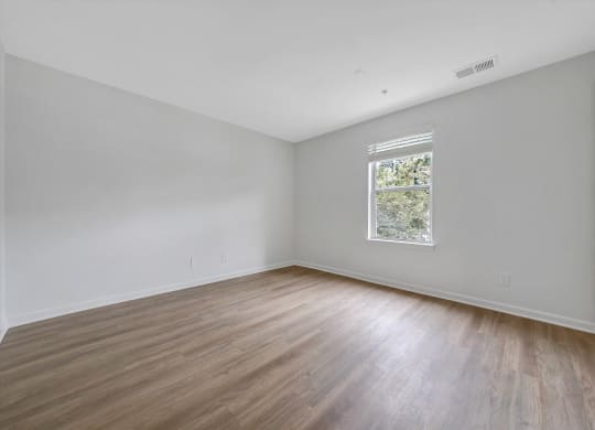 a bedroom with white walls and hardwood floors at The Vinings Apartments, Richmond, VA