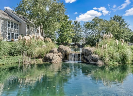 a pond with a waterfall in front of a house at Trophy Club at Bellgrade, Midlothian, VA, 23113