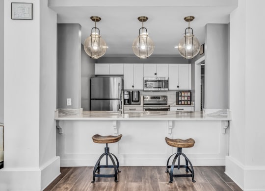 a kitchen with white cabinets and a bar with two stools at Trophy Club at Bellgrade, Midlothian, VA, 23113