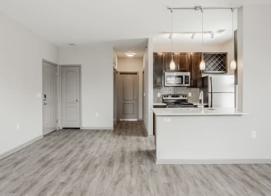 an empty living room and kitchen with white walls and wood flooring at The Avenue at Polaris Apartments, Columbus, OH