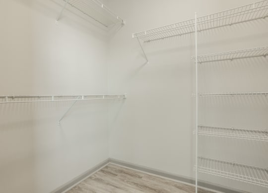 an empty closet with white walls and shelves and a wood floor at The Avenue at Polaris Apartments, Columbus, OH