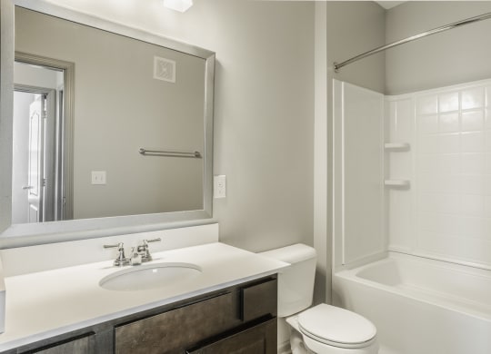 a bathroom with a sink toilet and shower and a mirror at The Avenue at Polaris Apartments, Columbus, OH