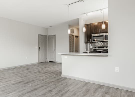 a living room with a white wall and a kitchen at The Avenue at Polaris Apartments, Columbus, OH