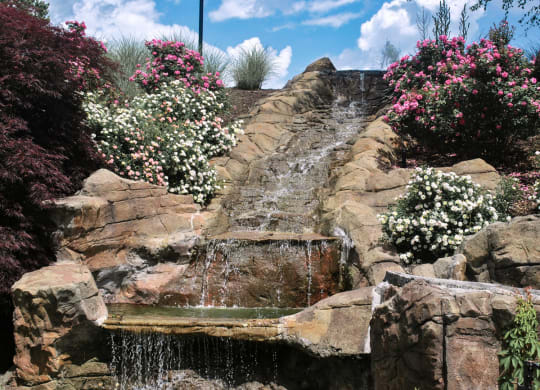 a small waterfall in a rock garden with flowers at The Vinings Apartments in Richmond, VA