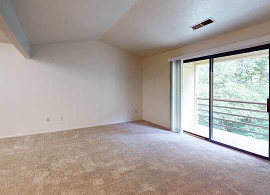 A living room with a high ceiling and a carpeted floor and sliding glass doors at Emerald Park Apartments, Michigan