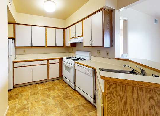 A kitchen with white appliances and wooden cabinets at Emerald Park Apartments in Kalamazoo, MI