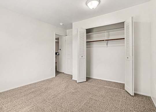 A white closet with a carpeted floor in a bedroom at Emerald Park Apartments, Kalamazoo, Michigan