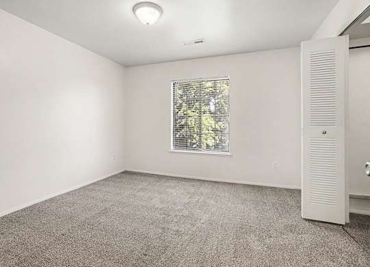 A bedroom with a window and a walk-in closet at Emerald Park Apartments, Kalamazoo, Michigan