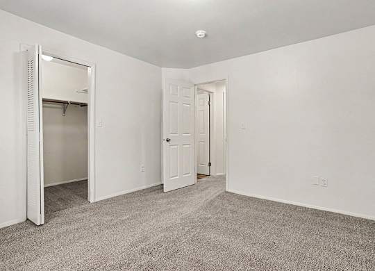 A spacious bedroom with a carpeted floor and a closet at Emerald Park Apartments, Kalamazoo, Michigan