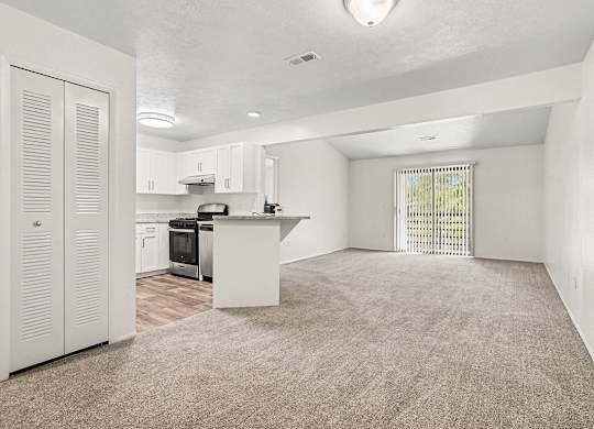 A kitchen with white cabinets and sliding glass doors to a balcony at Emerald Park Apartments, Kalamazoo, Michigan