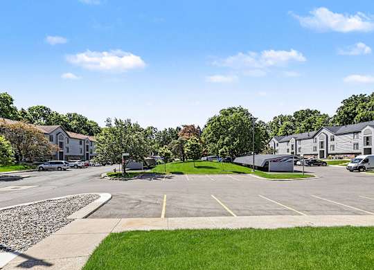A sunny day at a residential area with apartment buildings and a parking lot at Emerald Park Apartments in Kalamazoo, MI