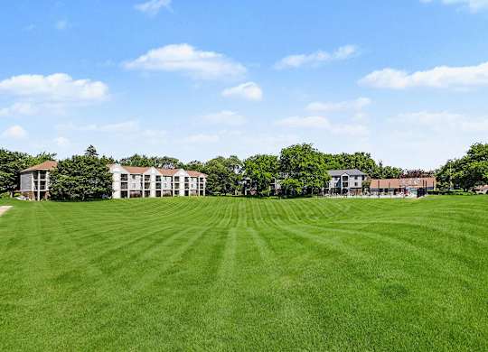 A large grassy field with a building in the background at Emerald Park Apartments in Kalamazoo, MI