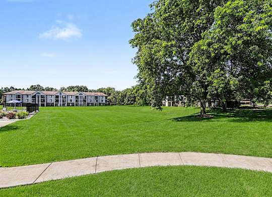A grassy area with a building in the background at Emerald Park Apartments in Kalamazoo, MI