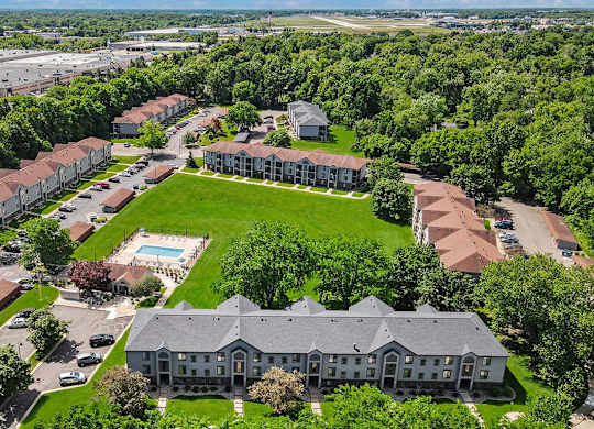 An aerial view of a large apartment building surrounded by trees and a pool at Emerald Park Apartments in Kalamazoo, MI