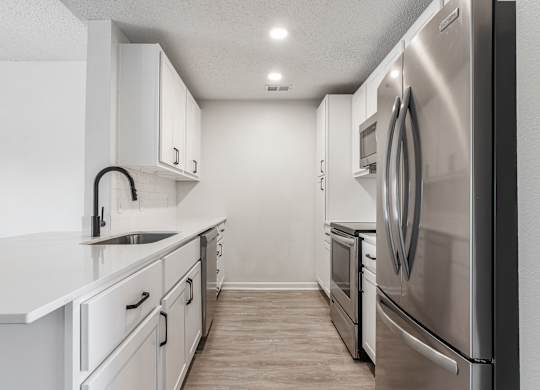an empty kitchen with white cabinets and stainless steel appliances at Latitudes Apartments, Indiana