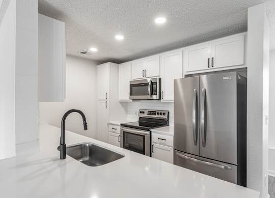 a kitchen with white cabinets and stainless steel appliances at Latitudes Apartments, Indiana, 46237