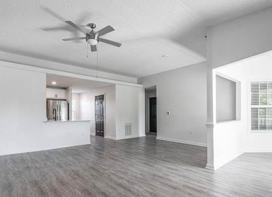 an empty living room and kitchen with a ceiling fan at Latitudes Apartments, Indiana