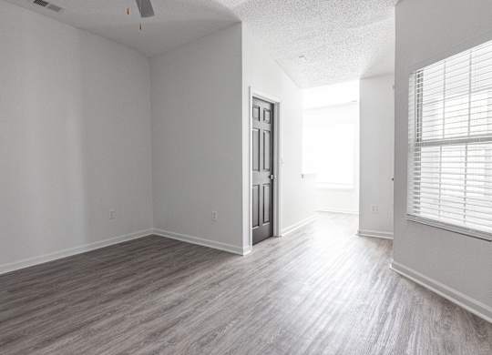 an empty living room with white walls and wood floors at Latitudes Apartments, Indianapolis, IN