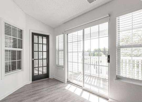 an empty living room with large windows and a door to a balcony at Latitudes Apartments, Indianapolis
