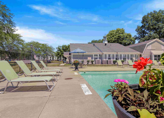 a pool with lounge chairs and a house in the background at Bay Pointe Apartments in Lafayette, IN