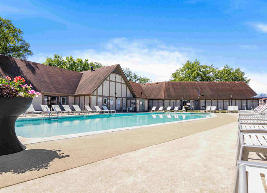 a swimming pool with chairs and a building in the background at Bay Pointe Apartments in Lafayette, 47909