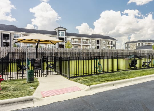 a fenced in yard with a playground and apartments in the background at The Avenue at Polaris Apartments, Columbus, OH