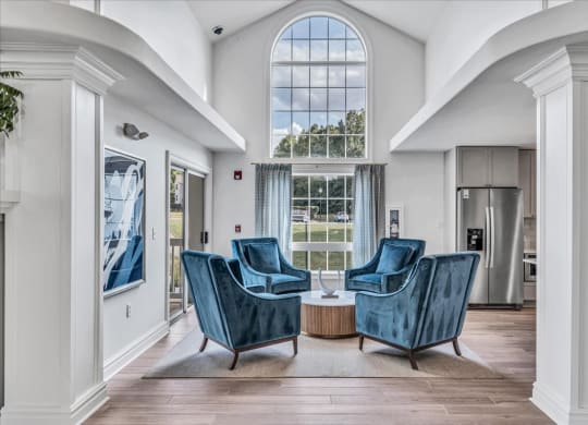 a living room with two blue chairs and a large window at The Vinings Apartments in Richmond, VA