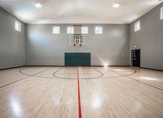 A basketball court with a green wall and a basketball hoop.