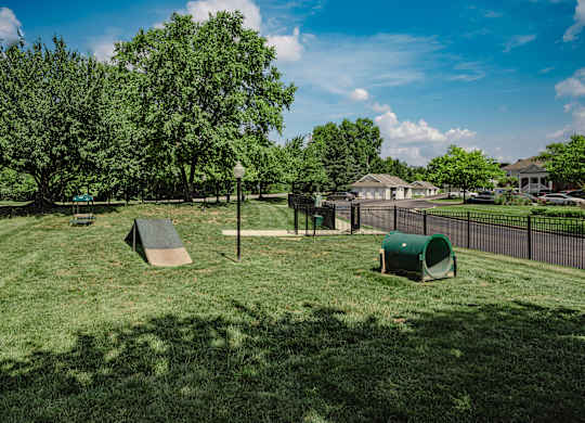 A playground with a slide and a green trash can.