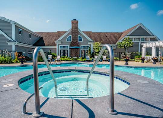 A swimming pool with a diving board in front of a house.