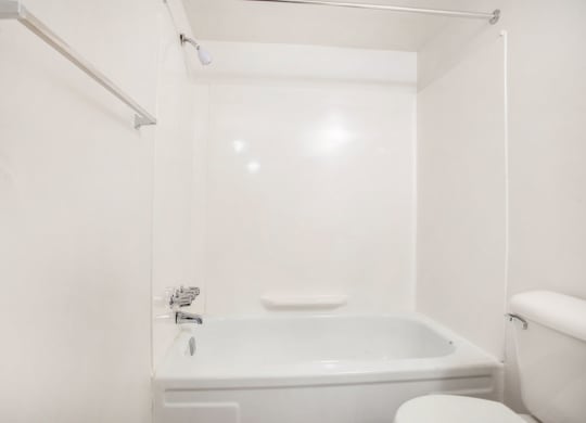 a white bathroom with a tub and a toilet at Fairlane Apartments in Springfield, MI