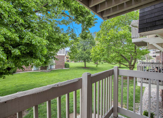 the view from a private balcony with mature shade trees at Fairlane Apartments in Springfield, MI
