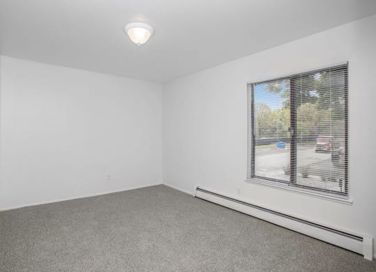 an empty bedroom with a large window at Fairlane Apartments in Springfield, MI