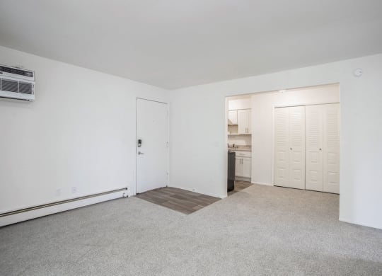 an empty living room with a kitchen in the background at Fairlane Apartments in Springfield, MI