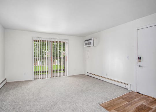 an empty living room with a slider to a private balcony at Fairlane Apartments in Springfield, MI