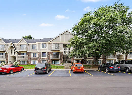 Parking lot with mature tree and apartment buildings at Fairlane Apartments, Springfield, MI 49037