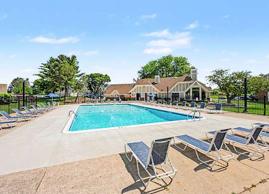 Outdoor swimming pool with lounge chairs and clubhouse at Fairlane Apartments, Springfield, MI