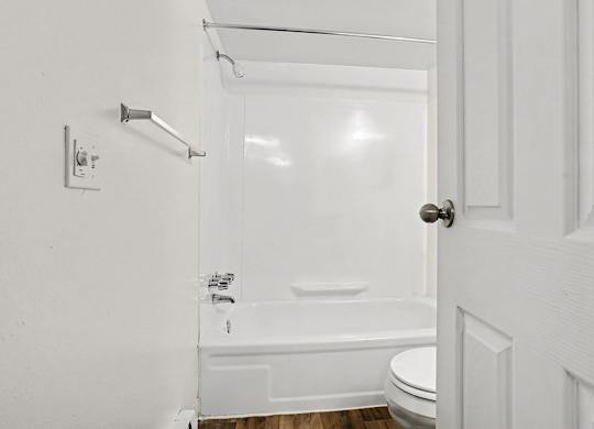 White bathroom with tub shower combo and chrome fixtures at Fairlane Apartments, Michigan, 49037